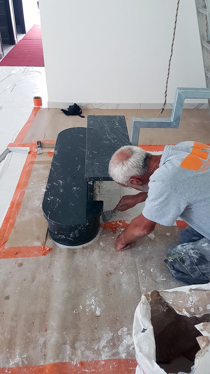 Artisan carreleur en action sur un escalier en marbre - L'Atelier du Carrelage Vire-Normandie