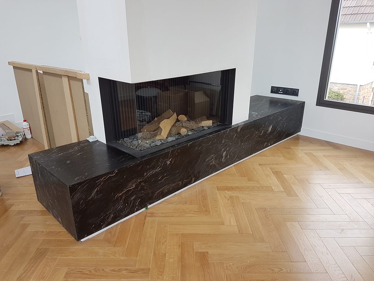 Habillage cheminée en marbre noir et parquet chevrons